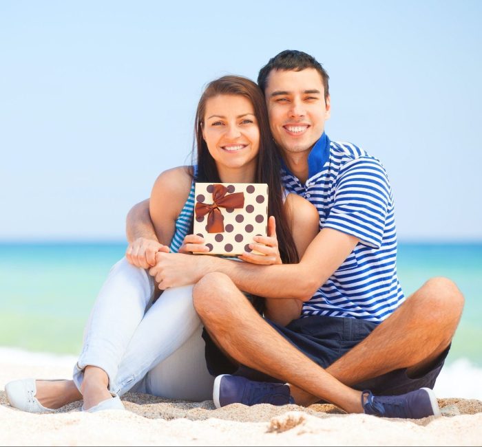 Young couple with gift on the beach in summer day.